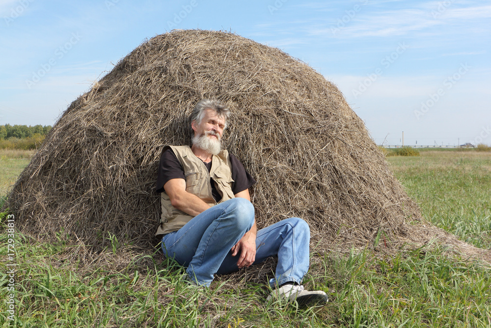 Man sleeping in a field near a haystack in the fall Man sleeping in a field near a haystack in the fall