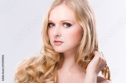 Portrait einer hübschen jungen Frau mit langen blonden Haaren vor weissem Hintergrund