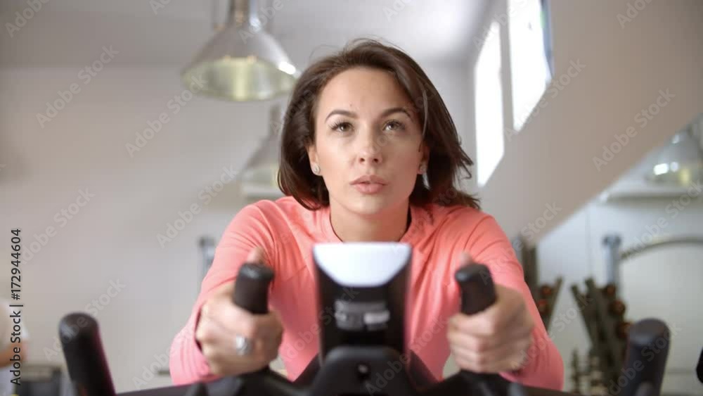 Woman on exercise bike in spinning class at a gym, close up Woman on exercise bike in spinning class at a gym, close up