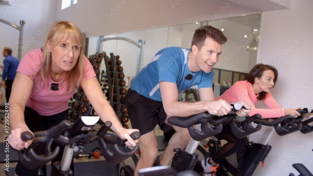 Side view of a spinning class on exercise bikes at a gym Side view of a spinning class on exercise bikes at a gym