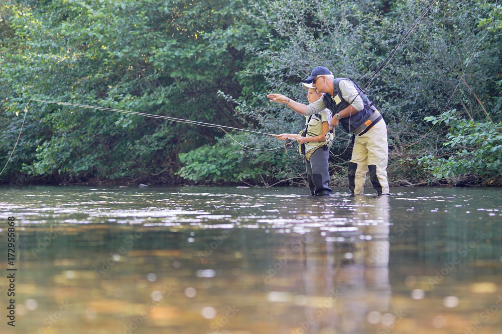 Father teaching son how to fly-fish in river