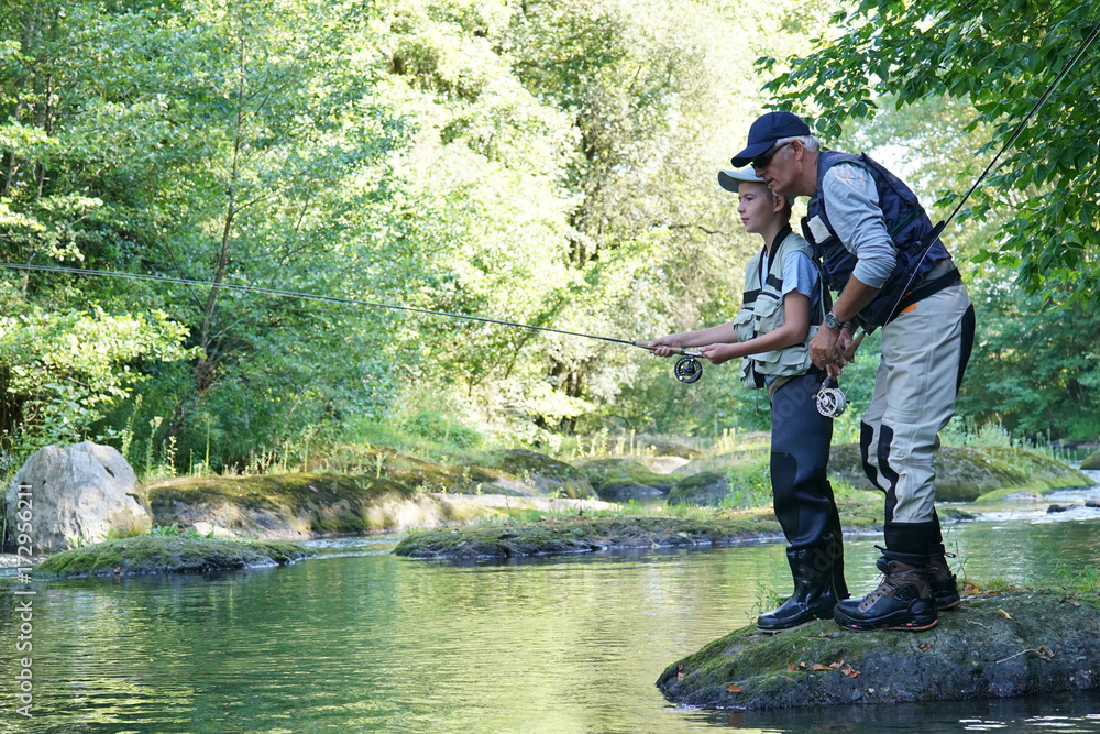 Dad with young boy fly-fishing in river Dad with young boy fly-fishing in river