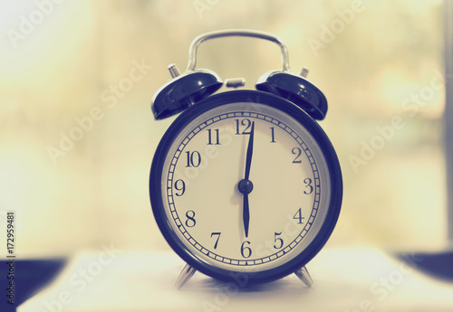 Alarm clock on wooden table with blrred background,retro effect