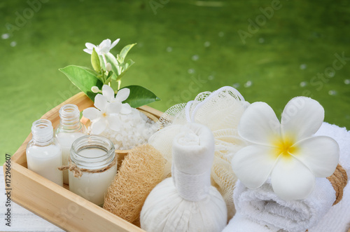 Spa wellness concept white candle milk soap salt towel flowers and herbal massage ball on white wood table with green pond background