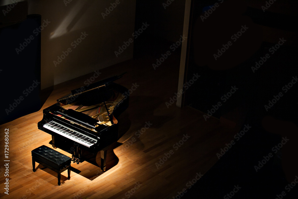 Fototapeta czarny fortepian w świetle punktowym w ciemnym pokoju