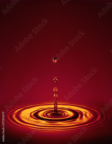 Droplet with ripples in red liquid