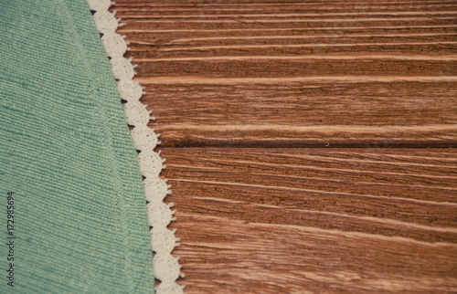 Handmade tablecloth with rough texture decorated with white lace, copy space on the right (on a worn wooden table), retro style