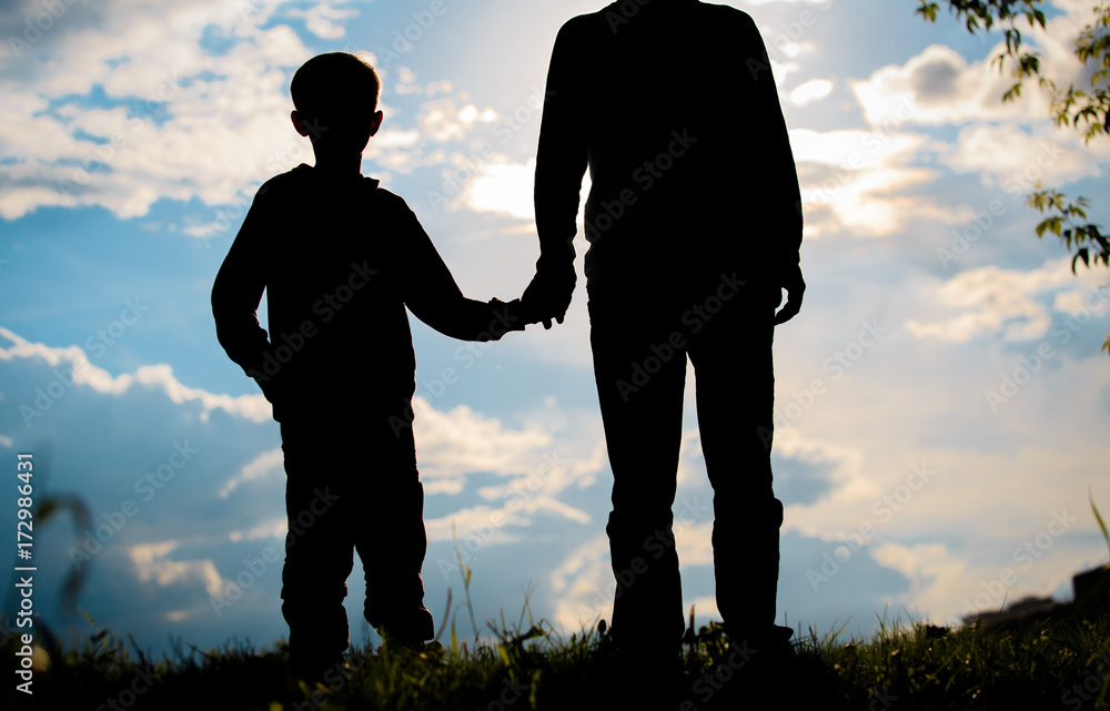 silhouette of father and son holding hands at sunset silhouette of father and son holding hands at sunset