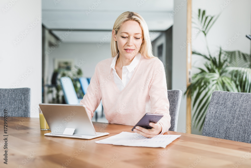 Businesswoman using cell phone and tablet in office Businesswoman using cell phone and tablet in office