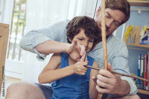 Father showing son how to use self-made bow and arrow