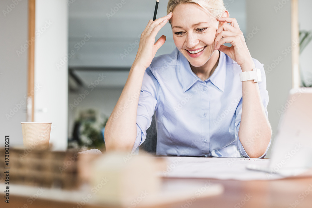 Smiling businesswoman working at desk in office Smiling businesswoman working at desk in office