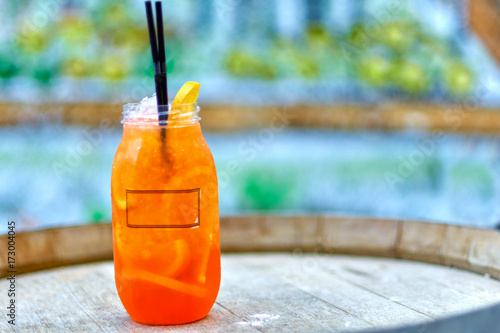 Cocktail Aperol-Spritz. A plastic glass with an orange wedge and drinking straw on a wooden barrel terrace outdoor restaurant. Traditional Italian aperitif from prosecco and liqueur Campari,Select photo