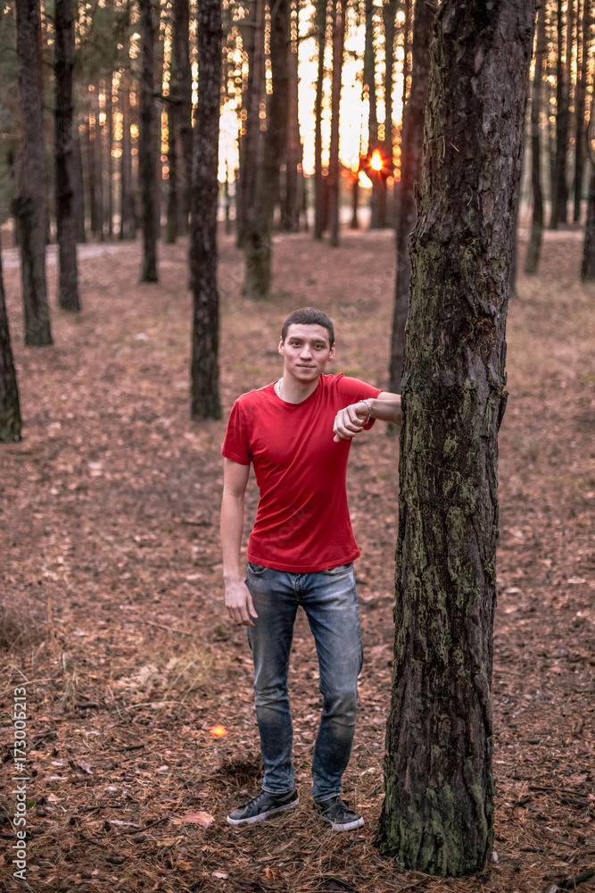 A young guy in a red T-shirt in a pine forest