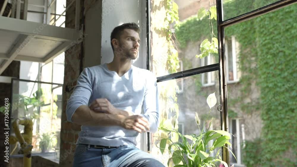 Handsome man in blue sweater leaning on window's sill and doing serious look to the camera, steadycam shot
Handsome man in blue sweater leaning on window's sill and doing serious look to the camera, steadycam shot
