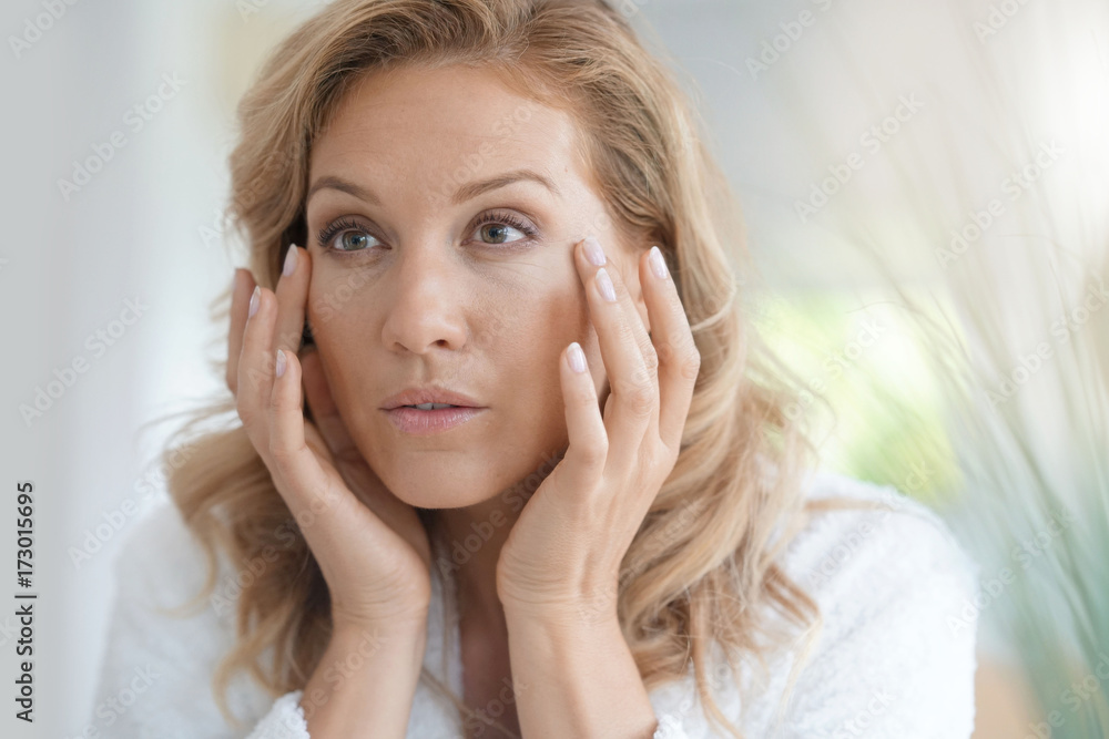 Portrait of attractive blond woman applying anti-aging cream Portrait of attractive blond woman applying anti-aging cream