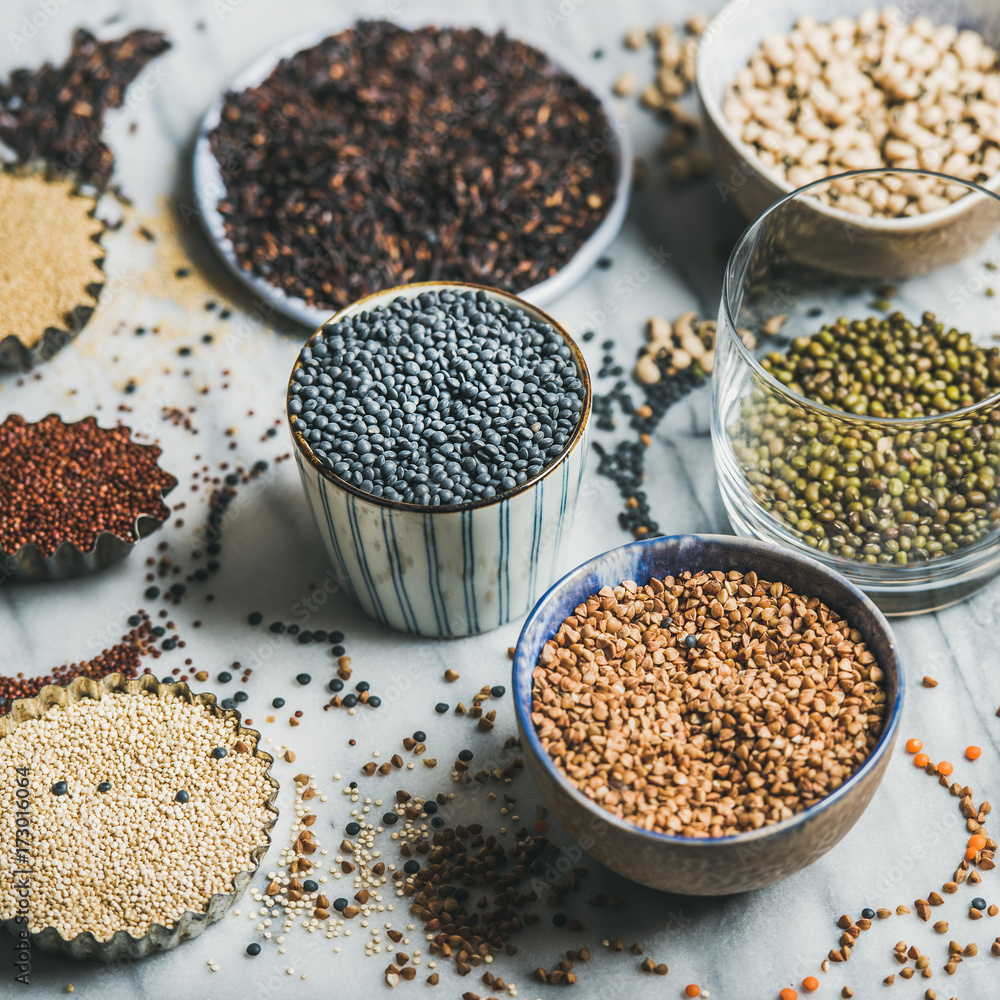 Various raw uncooked grains, beans, cereals in bowls, cups and glass for healthy cooking over marble background, selective focus, square crop. Clean eating, dieting, healthy, detox, vegan food concept Various raw uncooked grains, beans, cereals in bowls, cups and glass for healthy cooking over marble background, selective focus, square crop. Clean eating, dieting, healthy, detox, vegan food concept