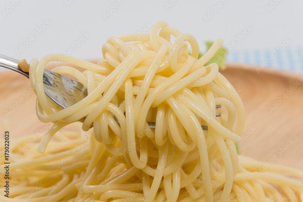 spaghetti without sauce with fork on wooden plate spaghetti without sauce with fork on wooden plate
