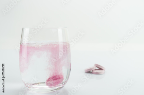 Glass of water with just disintegrating pink tablet
