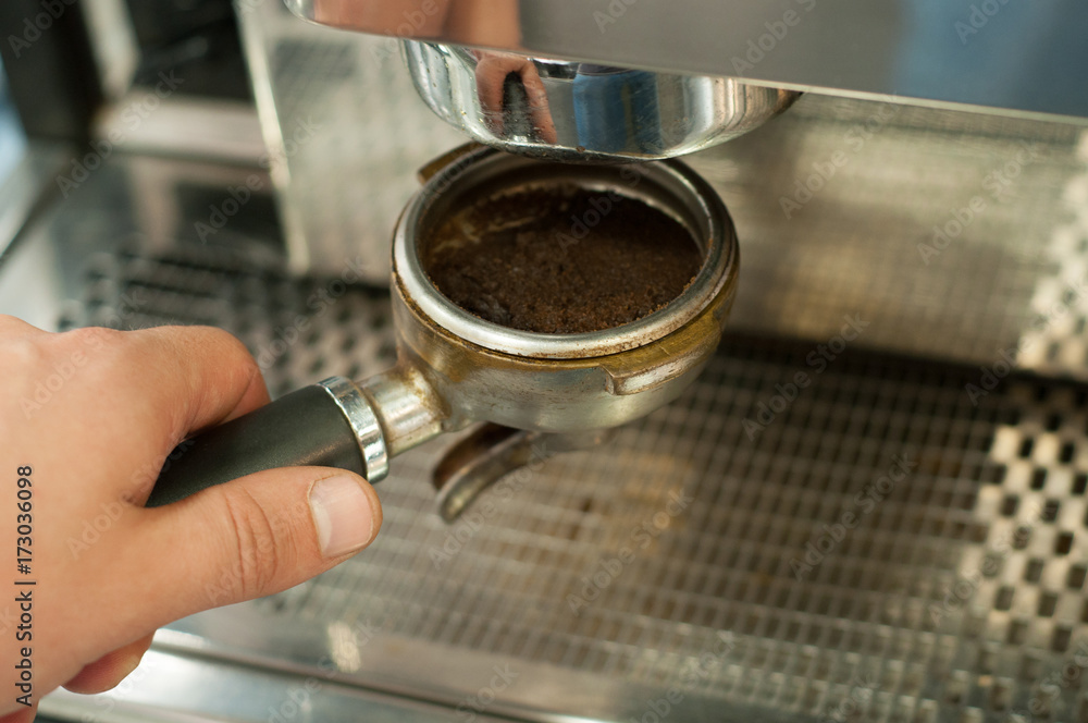 Barista prepares espresso, holding a holder of a coffee machine