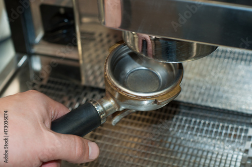 Barista prepares espresso, holding a holder of a coffee machine