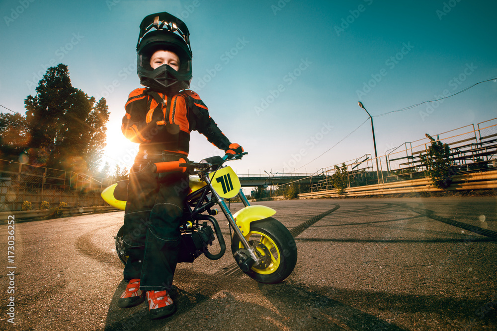 Child on his small motorcycle. Small biker dressed in a protective