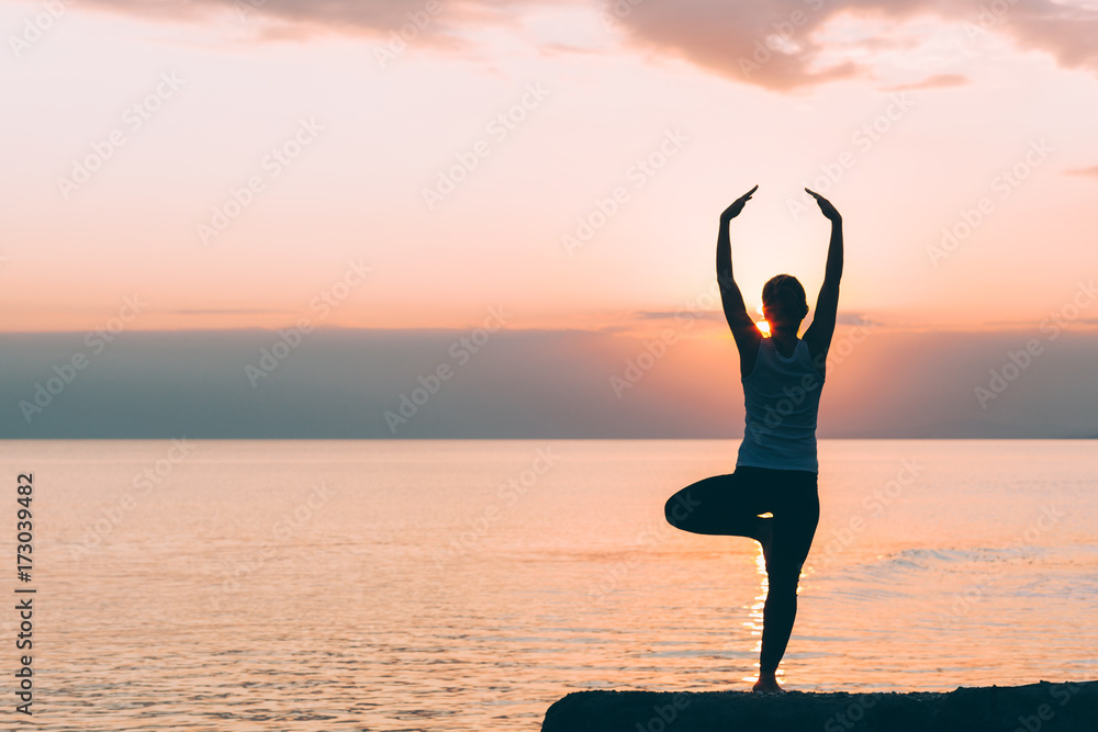 Young woman doing yoga by the sea