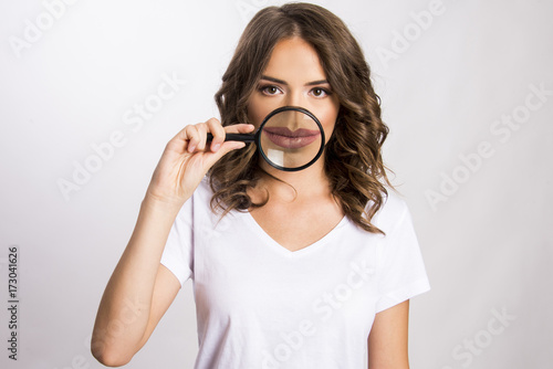 Young girl holding magnifier over her mouth 