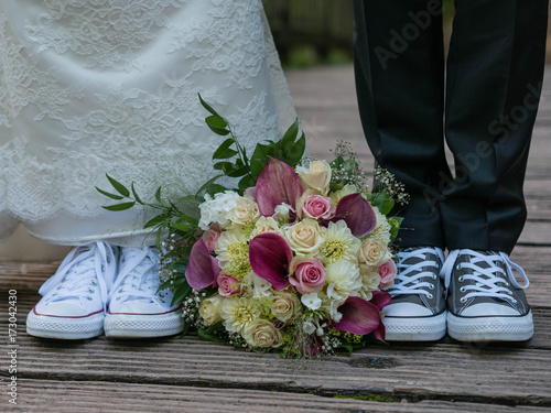 Fotografía Brautpaar mit lustigen Hochzeitsschuhen und wunderschönem Brautstrauss
