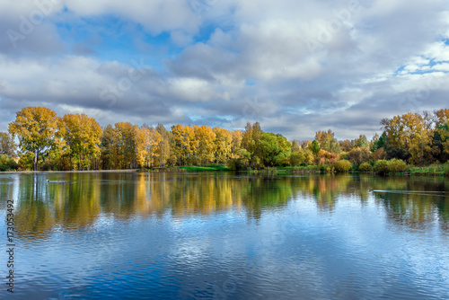 The lake, reflecting the cloudy sky and autumnal foliage trees