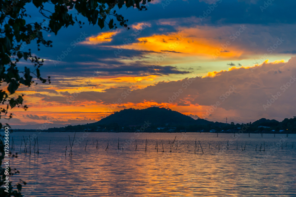 Sunset view from Songkhla lake, Southern Thailand, with cloudy sky and trees.