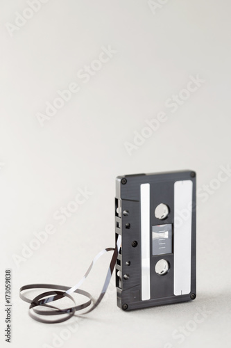 Single audio cassette tape with loose tape spilling from top cassette.