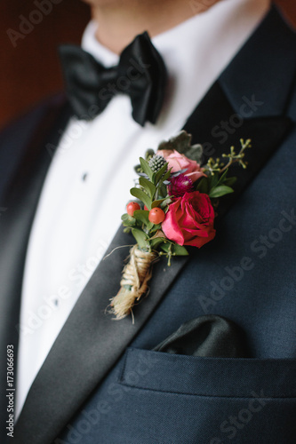 Mid section of a groom wearing tuxedo with boutonniere