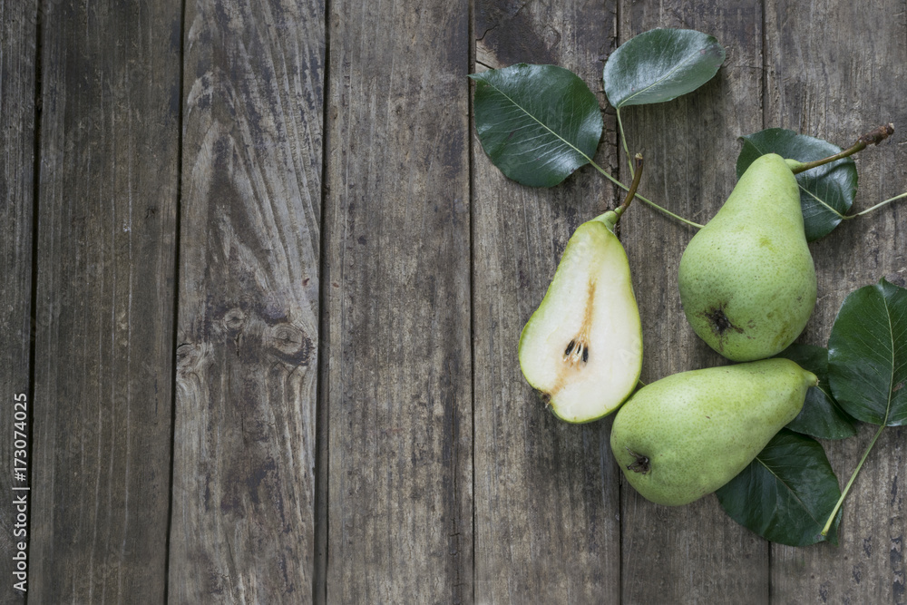 Green pears with leafs on old, wooden table. High angle view