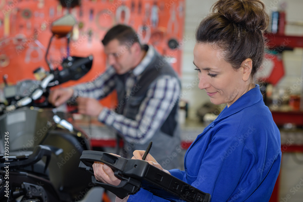 female repairing motorcycle in a garage