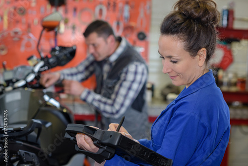 female repairing motorcycle in a garage
