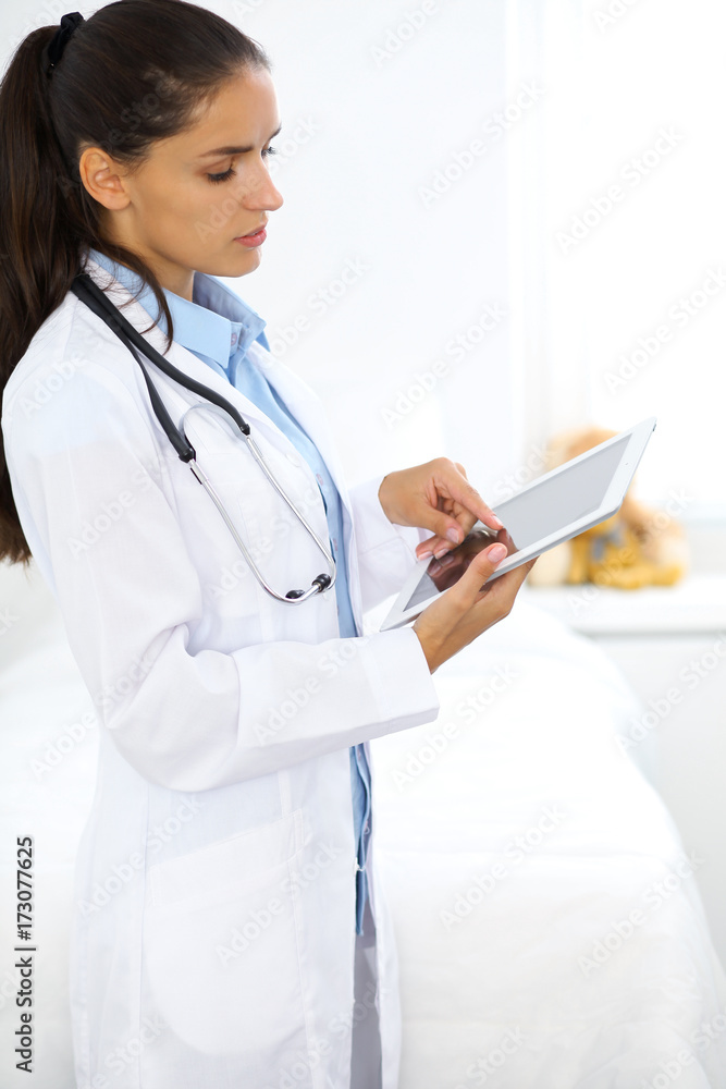 Young brunette female doctor standing and smiling at hospital Young brunette female doctor standing and smiling at hospital