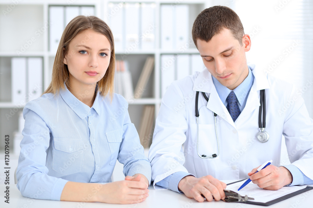 Doctor and patient sitting at the desk. Medicine and health care concept Doctor and patient sitting at the desk. Medicine and health care concept