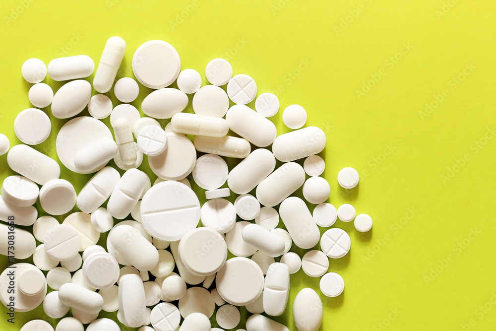 White medicine pills on a green and yellow background White medicine pills on a green and yellow background