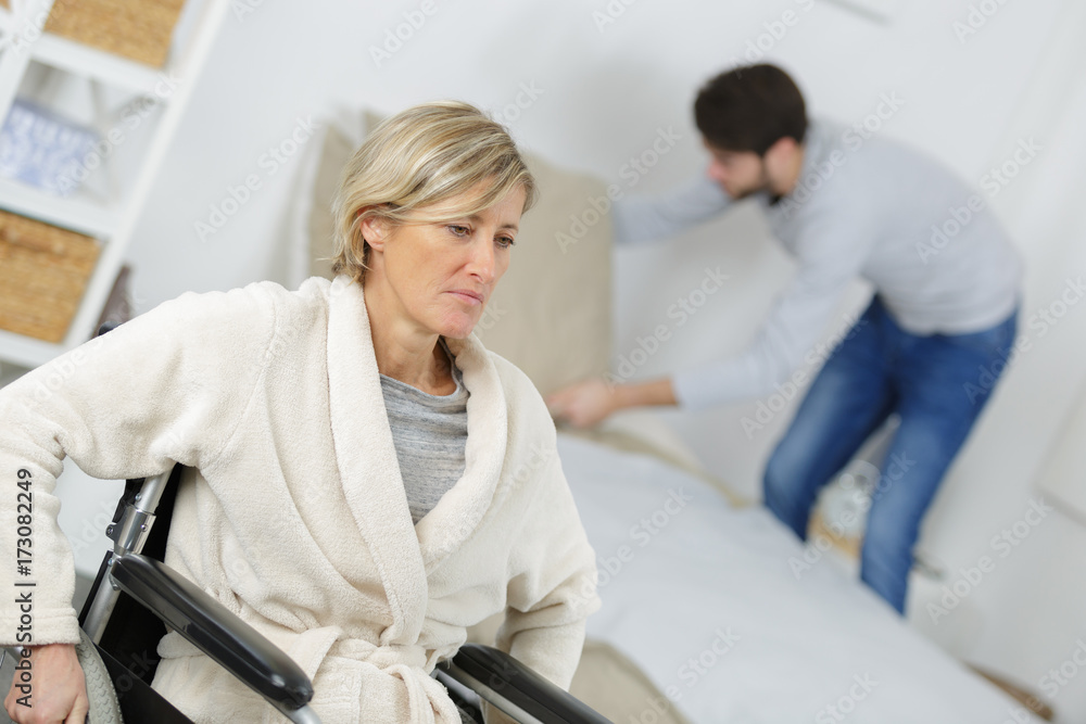 woman in wheelchair with young man in the background woman in wheelchair with young man in the background