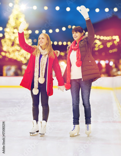 women waving hands at christmas skating rink