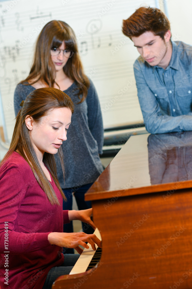 a music teacher with two pupils during piano lesson a music teacher with two pupils during piano lesson