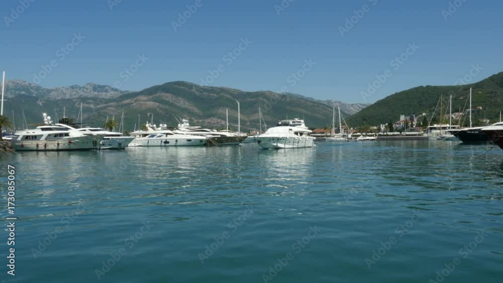 Moored yachts on seaport. Yacht moving through the sea port Montenegro Moored yachts on seaport. Yacht moving through the sea port Montenegro