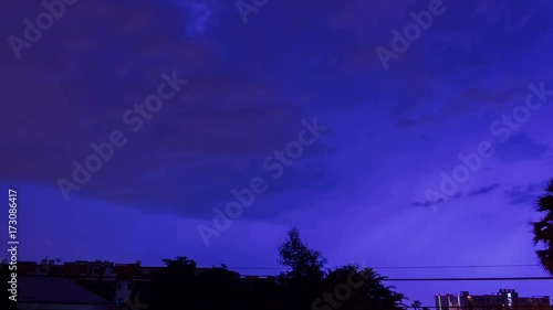 Storm clouds with lightning strike bolts passing over night city of Bangkok cityscape. 4K Timelapse