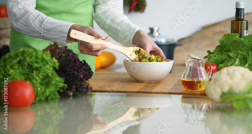 Closeup of human hands cooking vegetables salad in kitchen on the glass table with reflection