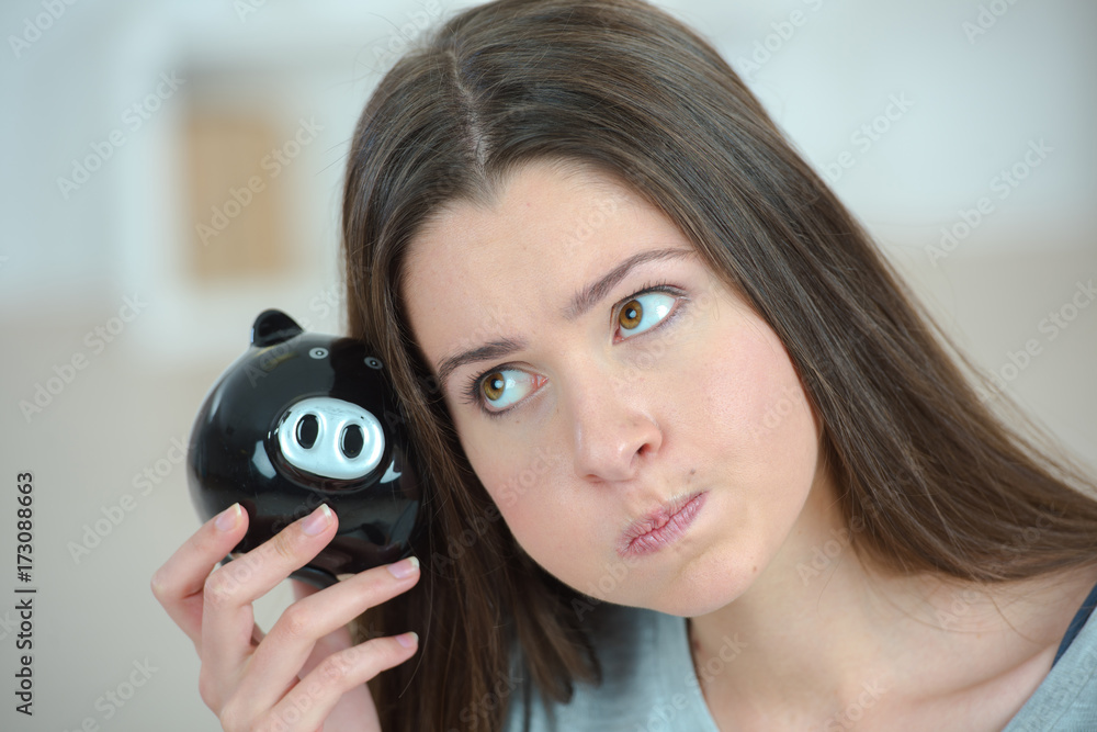 Fototapeta premium woman looking weird holding a piggy bank