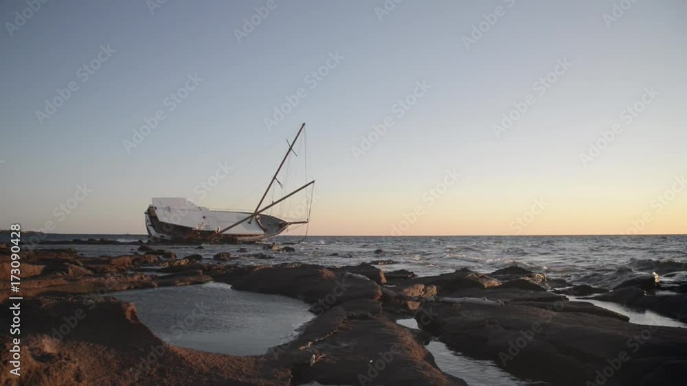 Sailboat stranded along the coast on the cliff of Sardinia in the Mediterranean Sea.