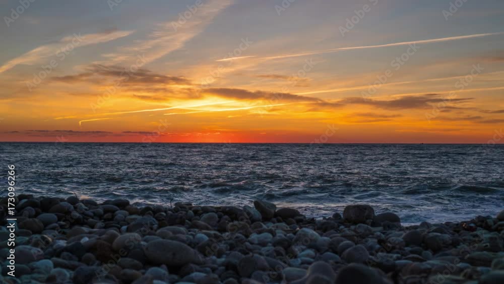 Timelapse of bright orange sun setting into the Black Sea. Sunset on a pebble beach Timelapse of bright orange sun setting into the Black Sea. Sunset on a pebble beach