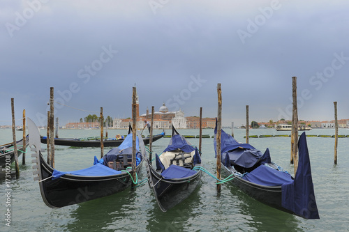 Traditional gondolas in the sea water on background of ancient Venice, Italy