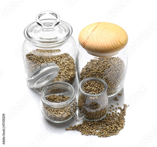 Glass jars with hemp seeds on white background