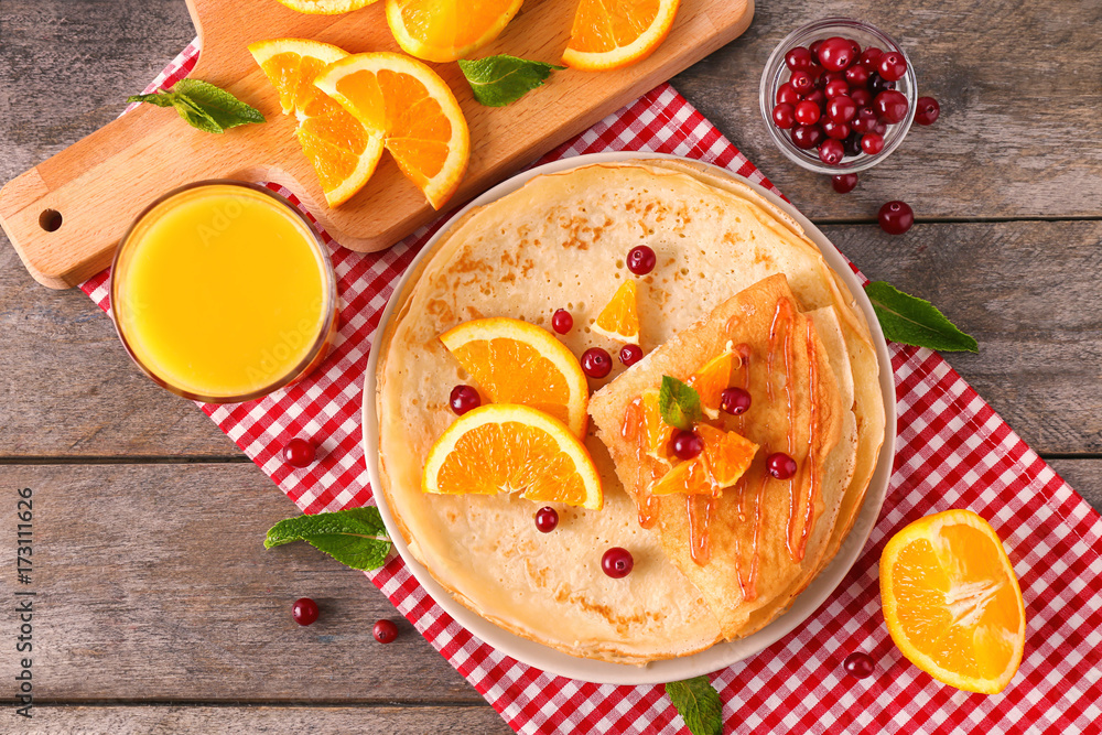 Delicious pancakes with orange and cranberry on wooden table Delicious pancakes with orange and cranberry on wooden table